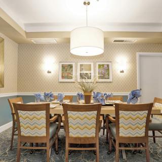 A well-decorated dining room with a central table and chairs, elegant lighting, and wall art.