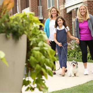 A family walking their dog in a residential neighborhood.