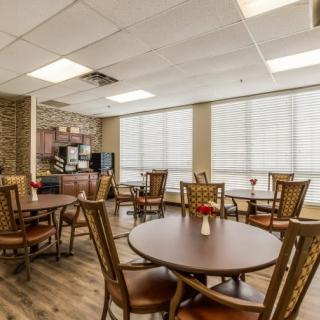 A bright and inviting dining area with several tables and chairs, featuring large windows allowing natural light to fill the room.
