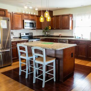 A modern kitchen featuring wooden cabinets, a central island with bar stools, and stylish pendant lighting.
