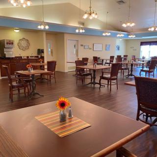 A well-lit restaurant interior with neatly arranged tables and chairs, featuring warm decor.
