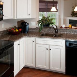 A modern kitchen with white cabinets and a dark countertop.