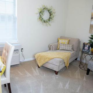 A cozy living room with a beige chaise lounge adorned with yellow accents, featuring a decorative wreath and natural lighting.