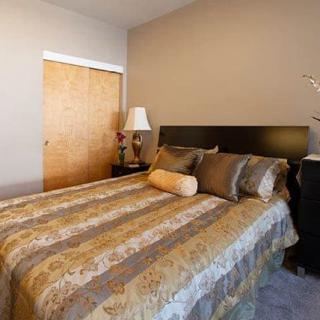 A cozy bedroom featuring a neatly made bed with decorative pillows and a bedside lamp.