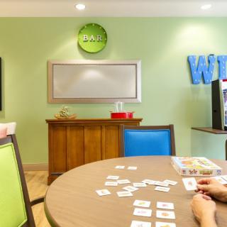 A vibrant game room featuring a table with cards, colorful chairs, and a whiteboard.