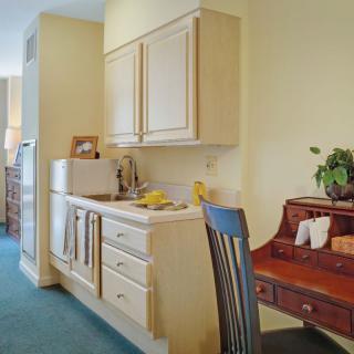 A compact kitchen area with wooden cabinets and a small desk for workspace.