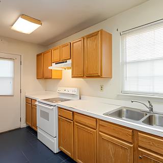 A clean and organized kitchen with wooden cabinets, a stove, and a double sink.