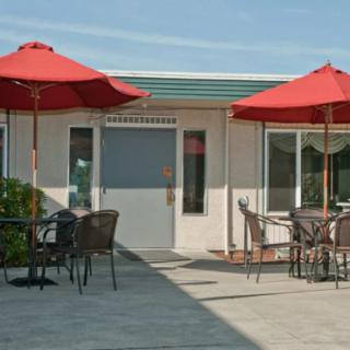 An outdoor patio area with red umbrellas and seating on a sunny day.