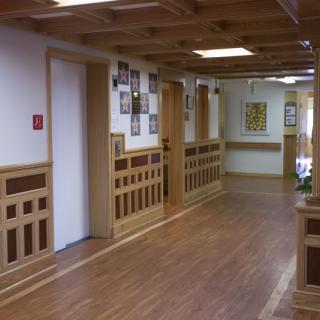 A hallway with wooden paneling and flooring in a building interior.