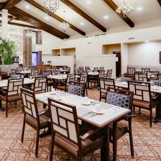 A spacious restaurant dining area with neatly arranged tables and elegant chandeliers.