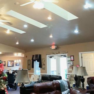 A cozy living room decorated with a Christmas tree, featuring comfortable furniture and overhead skylights.