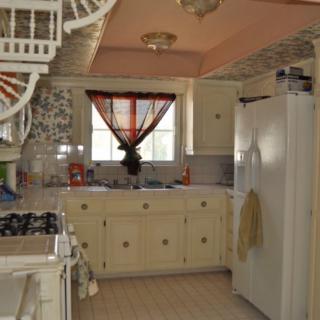 A vintage-style kitchen with cream cabinets and a classic white fridge.