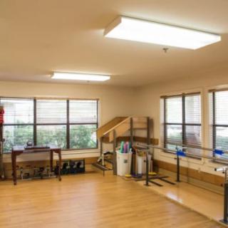 A rehabilitation room equipped with exercise equipment and parallel bars.