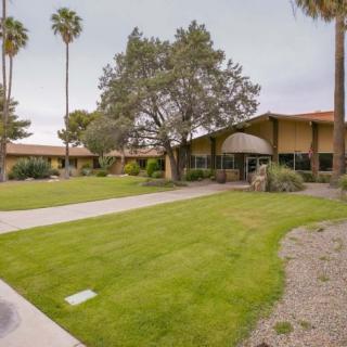A scenic view of a building surrounded by a well-kept lawn and tall palm trees.