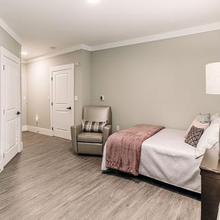 A minimalist bedroom with a single bed, armchair, and neutral color scheme.