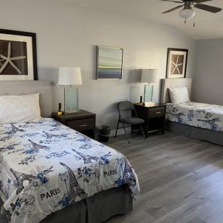 A tidy bedroom with two single beds, decorated with blue and white bedding, featuring lamps and artwork on the walls.