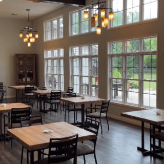 A modern restaurant interior with wooden tables and large windows.