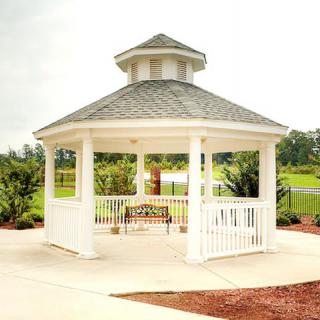 A white gazebo with a bench inside, set in a scenic outdoor park.