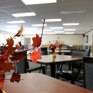 A cozy dining area decorated with autumn-themed centerpieces, featuring tables set for community gatherings.