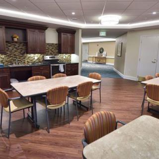 A modern kitchen and dining area featuring wooden tables and chairs with wood flooring.