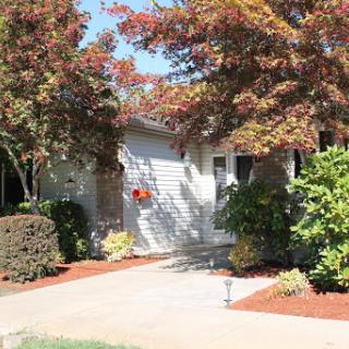 A charming residential home with well-maintained landscaping and vibrant trees.