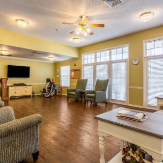 A cozy living room with large windows, comfortable seating, and a television.
