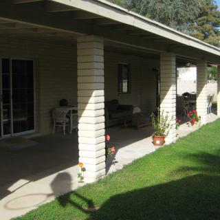 A sunny porch with columns, outdoor furniture, and a well-maintained lawn.