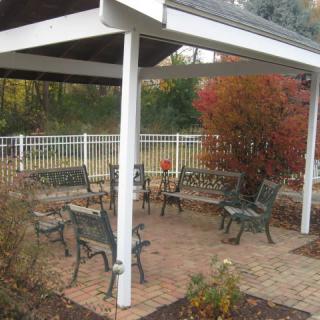 A cozy outdoor pergola with benches surrounded by autumn foliage.
