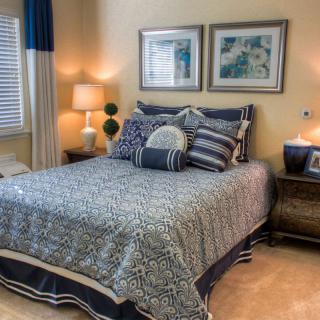A cozy bedroom with a neatly made bed, decorative pillows, and ambient lighting.