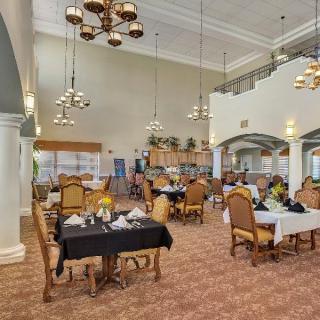 A spacious dining room with elegant chandeliers and neatly arranged tables and chairs.