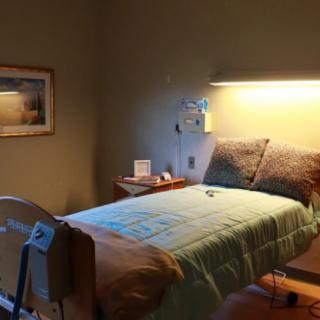 A dimly lit hospital room featuring a single bed and medical equipment.