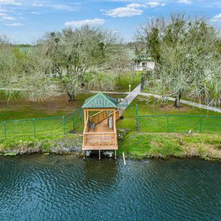 A serene lakeside view featuring a wooden dock surrounded by lush greenery and trees.