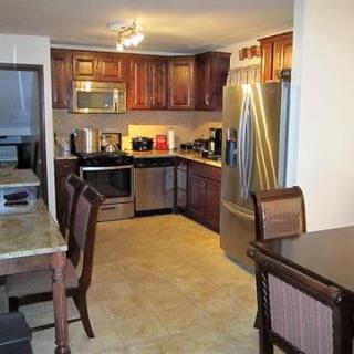 A modern kitchen with wooden cabinets and stainless steel appliances, featuring a dining area with a table and chairs.