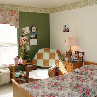 A cozy bedroom with floral decor and a comfortable armchair.