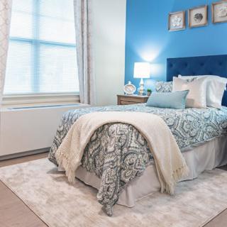 A cozy bedroom with a blue accent wall and elegant decor.