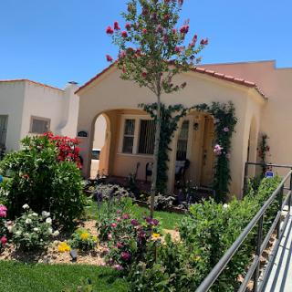 A charming house with a vibrant garden on a sunny day.