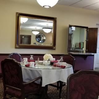 A cozy dining room with an elegantly set table and a large mirror reflecting the space.