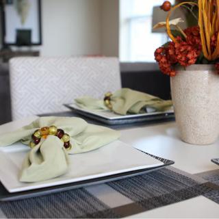 A neatly arranged dining table with green napkins and an elegant centerpiece.