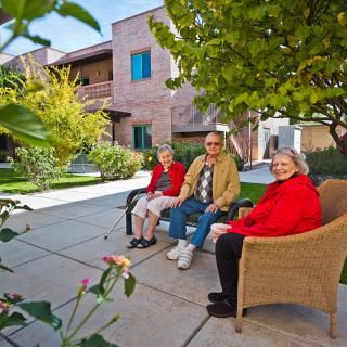 A group of seniors sitting and enjoying the outdoor garden area in a community setting.