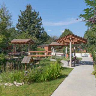 A serene garden with a concrete pathway, surrounded by lush greenery and wooden gazebos.