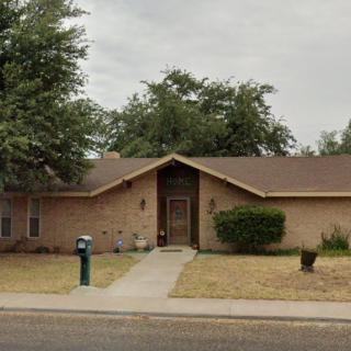 A suburban brick house with a driveway and front yard.