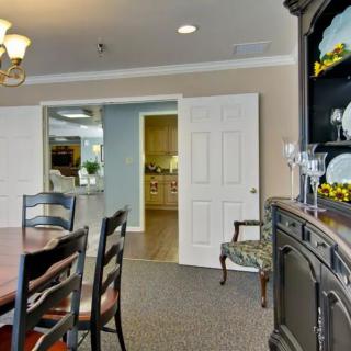 A well-furnished dining room featuring a table, chairs, and a cabinet with decorative items.