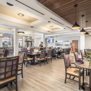 A modern restaurant interior with neatly arranged tables and chairs under warm lighting.