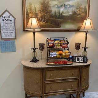 A decorated table featuring snacks, two lamps, and a landscape painting.