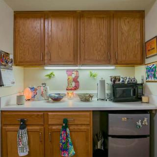 A compact kitchen setup with wooden cabinets, a microwave, and a mini fridge.
