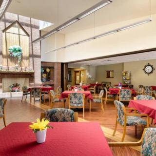 A cozy dining area with red tablecloths, comfortable chairs, and a fireplace.