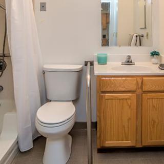 A clean and simple bathroom with a toilet, sink, and shower.