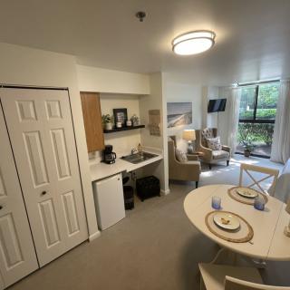 A cozy studio apartment featuring a kitchenette, dining area, and a living room with natural light.