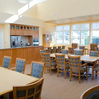 A bright dining area with wooden tables and chairs, featuring abundant natural light.