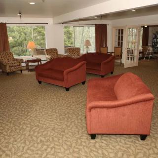 A cozy lounge area with red sofas and large windows overlooking greenery.